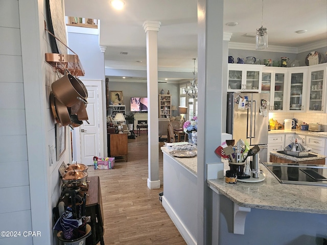 kitchen with high end fridge, light wood-type flooring, white cabinets, and light stone countertops