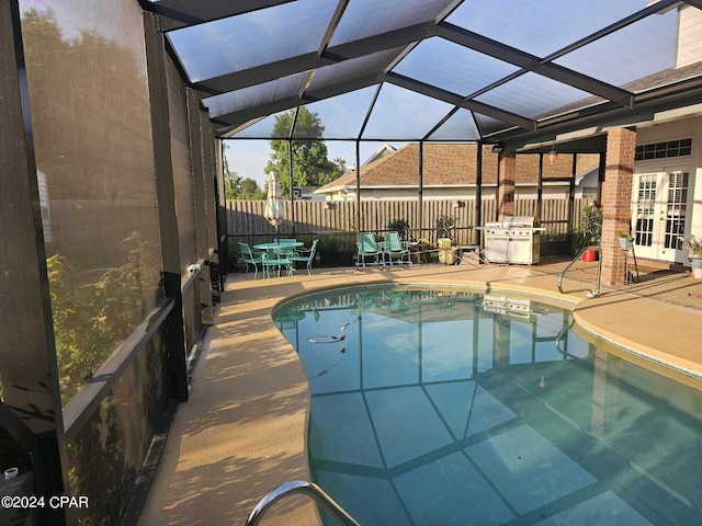 view of pool featuring glass enclosure, a grill, french doors, and a patio area