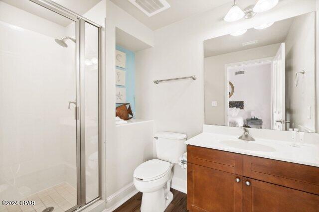 bathroom with an enclosed shower, vanity, hardwood / wood-style flooring, and toilet