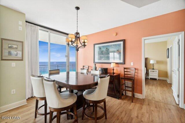 dining area with a water view, floor to ceiling windows, a chandelier, and light wood-type flooring