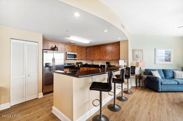 kitchen with sink, appliances with stainless steel finishes, a kitchen breakfast bar, light hardwood / wood-style floors, and kitchen peninsula