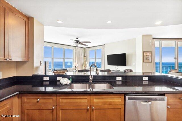 kitchen featuring dishwasher, sink, dark stone countertops, and ceiling fan