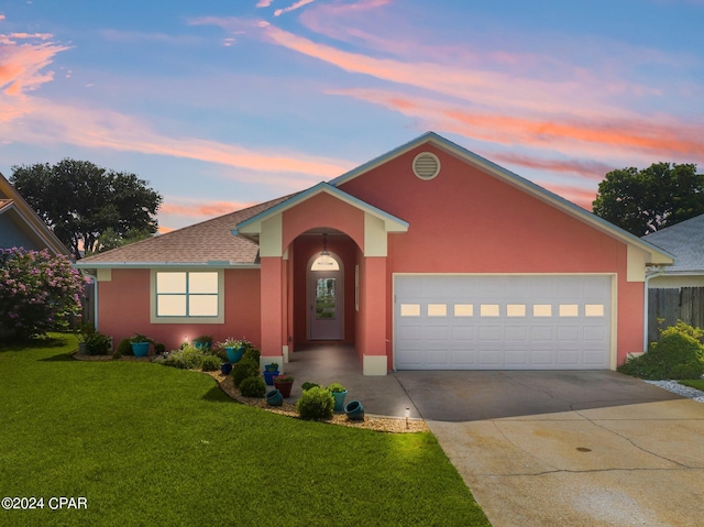 single story home featuring an attached garage, driveway, a lawn, roof with shingles, and stucco siding