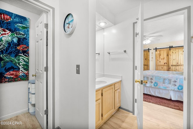 ensuite bathroom featuring ensuite bathroom, a ceiling fan, vanity, wood finished floors, and baseboards