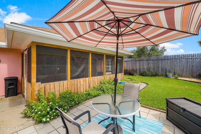 view of patio with outdoor dining space, fence, and a sunroom