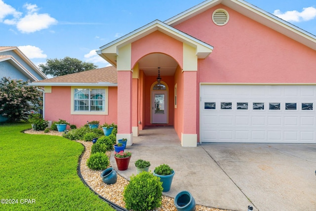 ranch-style house with a garage, a shingled roof, driveway, stucco siding, and a front yard