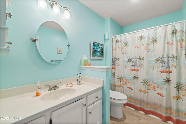 bathroom with curtained shower, toilet, a textured ceiling, vanity, and wood finished floors