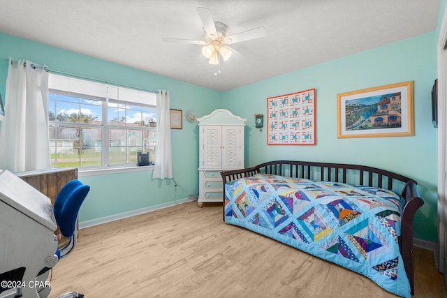 bedroom with light wood-style floors, ceiling fan, a textured ceiling, and baseboards