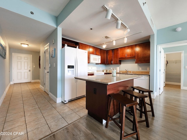 kitchen featuring white appliances, light wood-type flooring, a center island, track lighting, and sink