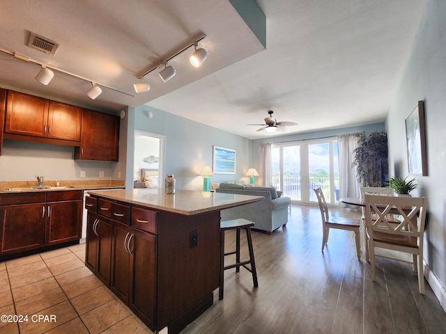 kitchen featuring a breakfast bar area, sink, rail lighting, a center island, and ceiling fan