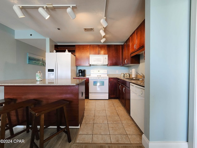 kitchen featuring white appliances, sink, light stone counters, light tile patterned floors, and rail lighting