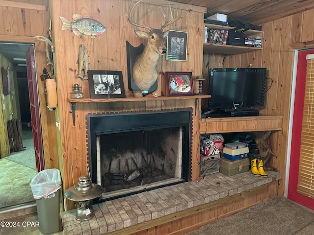 carpeted living room with a fireplace and wooden walls