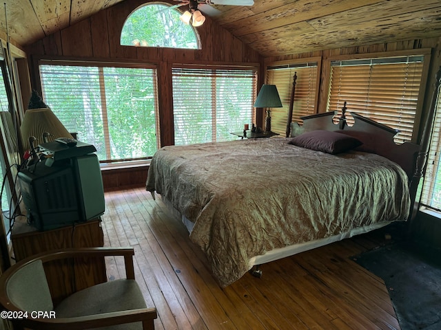 bedroom featuring ceiling fan, hardwood / wood-style flooring, wood walls, lofted ceiling, and wood ceiling