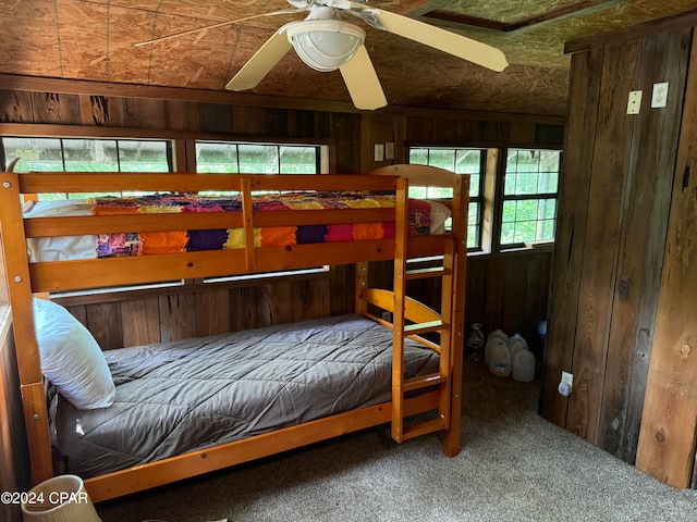 bedroom with carpet flooring, wooden walls, and ceiling fan