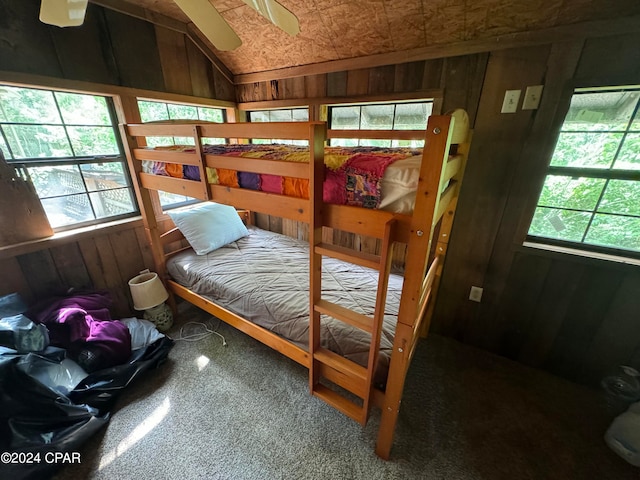 bedroom with wood walls, carpet floors, lofted ceiling, and ceiling fan