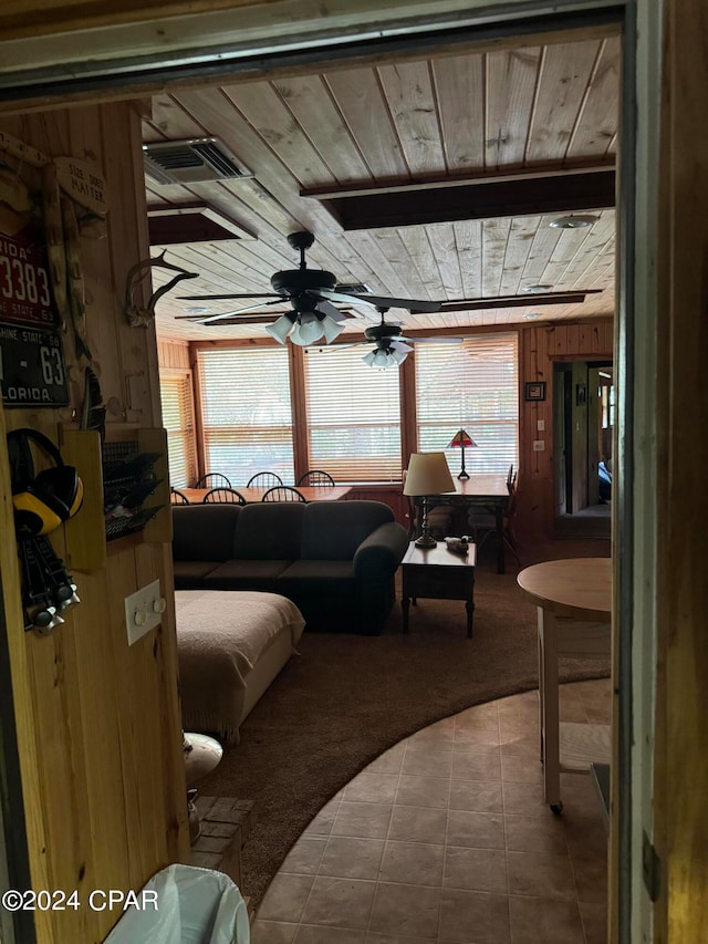 living room with tile patterned floors, wood walls, ceiling fan, and a wealth of natural light