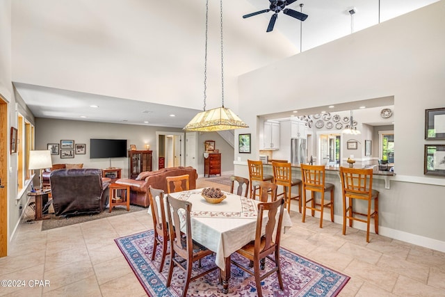 dining room with a high ceiling, ceiling fan, and light tile patterned floors