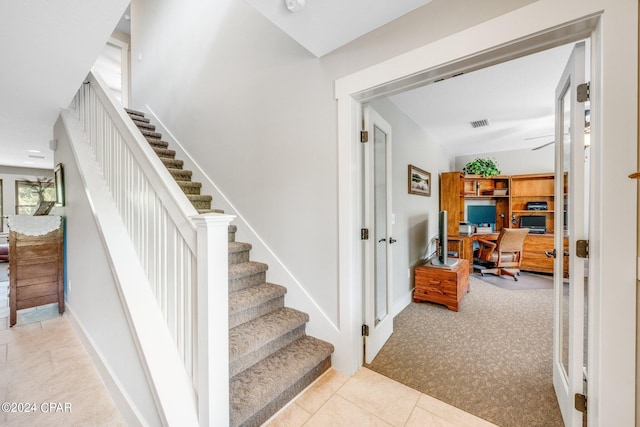 stairs featuring light tile patterned floors and ceiling fan