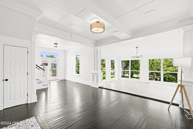 unfurnished living room with a notable chandelier, decorative columns, and dark wood-type flooring