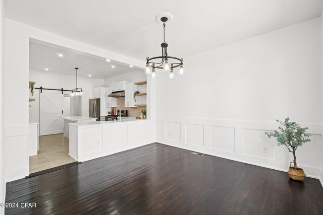 interior space featuring sink, a barn door, hardwood / wood-style flooring, and a chandelier