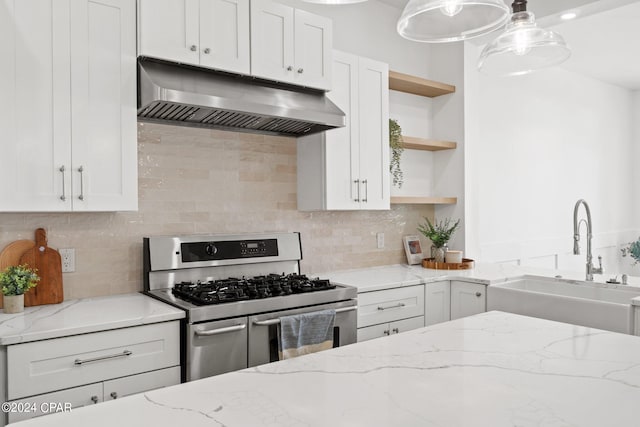 kitchen with range with two ovens, sink, light stone counters, hanging light fixtures, and backsplash