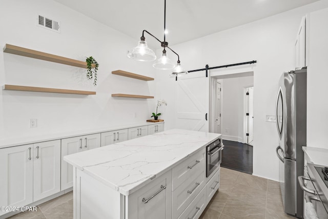 kitchen featuring white cabinetry, a center island, a barn door, appliances with stainless steel finishes, and light tile patterned floors