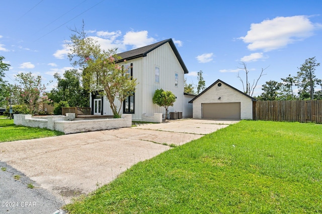 modern farmhouse style home with cooling unit, an outbuilding, a garage, and a front lawn