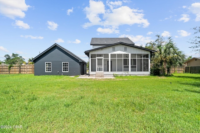 back of property with a sunroom and a lawn