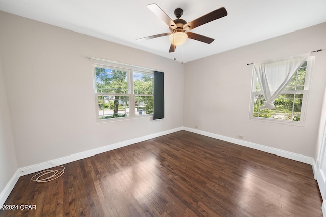 spare room featuring a wealth of natural light, ceiling fan, and dark wood-type flooring