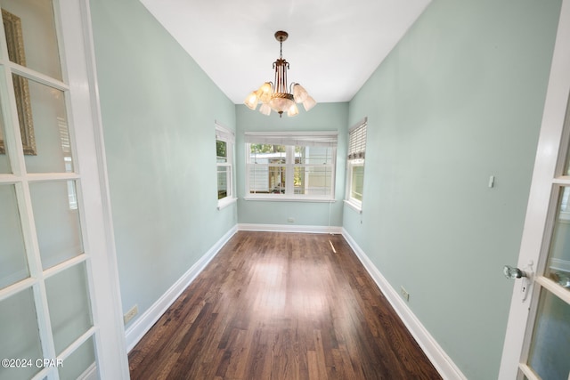 unfurnished dining area with dark hardwood / wood-style floors and an inviting chandelier