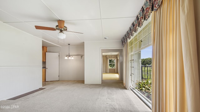 empty room featuring ceiling fan with notable chandelier and carpet floors