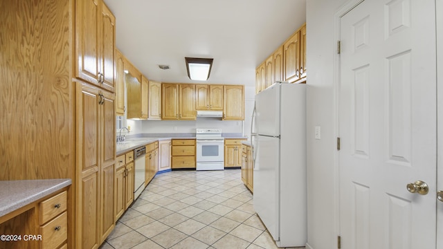 kitchen with light brown cabinetry, sink, light tile patterned floors, and white appliances