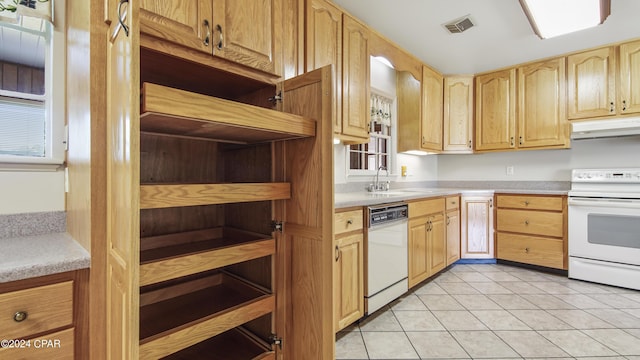 kitchen with light tile patterned flooring, white appliances, sink, and light brown cabinetry