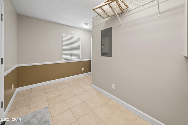 tiled spare room featuring electric panel and a textured ceiling