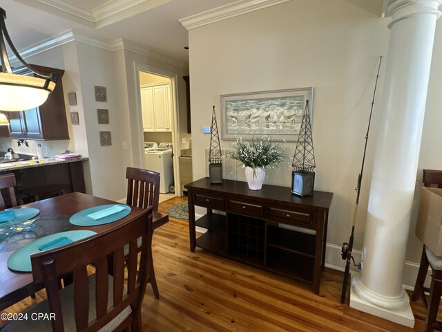 dining room with ornamental molding, wood-type flooring, decorative columns, and independent washer and dryer