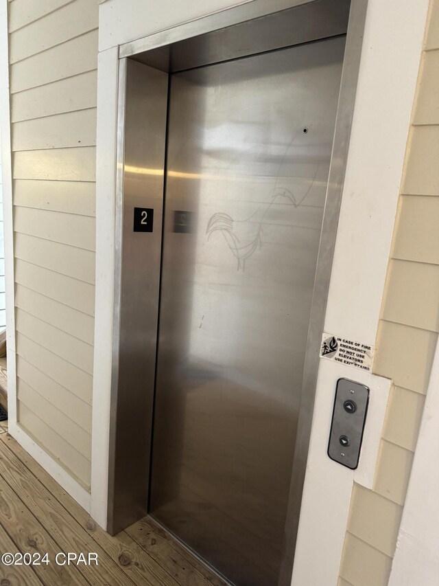 interior details featuring hardwood / wood-style floors, elevator, and wood walls