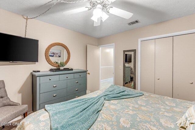 bedroom with ceiling fan, a closet, tile patterned flooring, and a textured ceiling