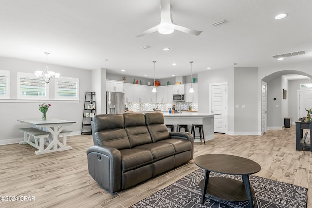 living room featuring ceiling fan with notable chandelier and light hardwood / wood-style floors