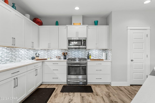 kitchen with backsplash, white cabinetry, light hardwood / wood-style flooring, and stainless steel appliances