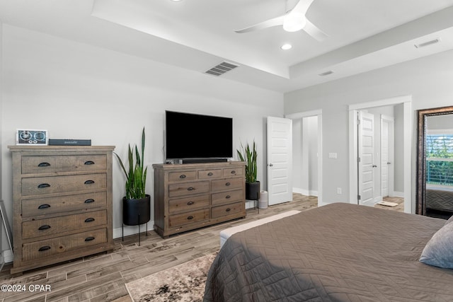 bedroom with a tray ceiling, ceiling fan, and light hardwood / wood-style flooring