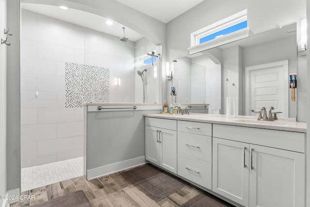 bathroom with hardwood / wood-style flooring, vanity, and tiled shower