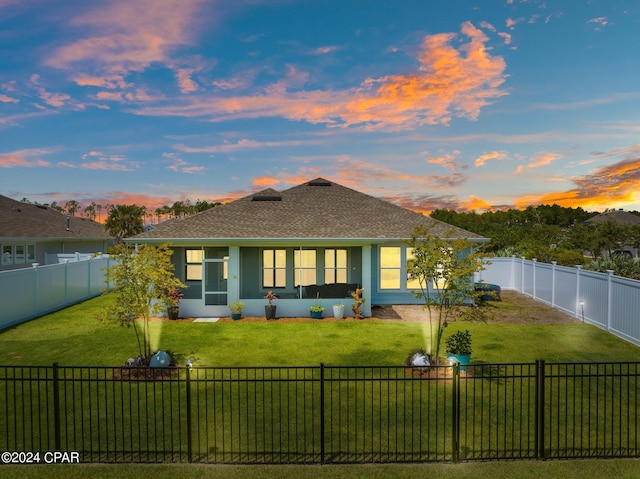 back house at dusk featuring a yard