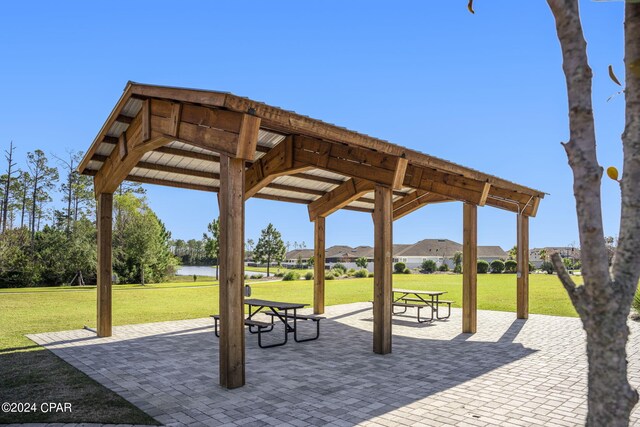 view of home's community with a patio area, a yard, and a water view