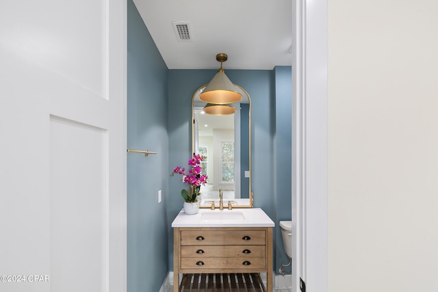 bathroom with toilet, visible vents, and vanity