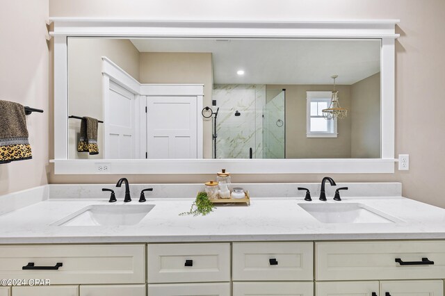 bathroom featuring a sink, a marble finish shower, and double vanity