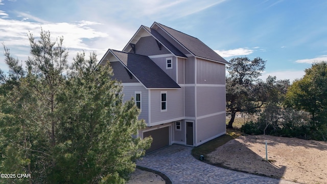 view of home's exterior with decorative driveway, an attached garage, and board and batten siding