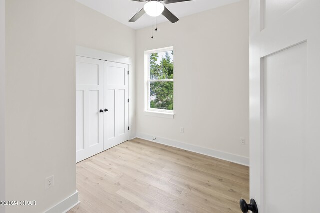 unfurnished bedroom featuring ceiling fan, a closet, and light wood-type flooring