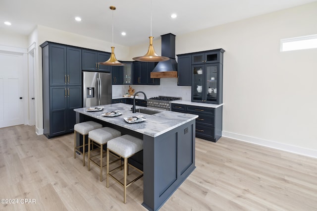 kitchen with pendant lighting, custom exhaust hood, sink, an island with sink, and appliances with stainless steel finishes