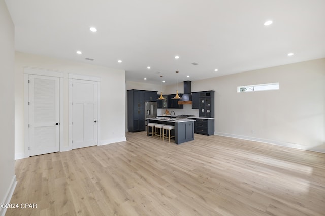 kitchen with a kitchen island with sink, premium range hood, a breakfast bar, open floor plan, and light wood finished floors