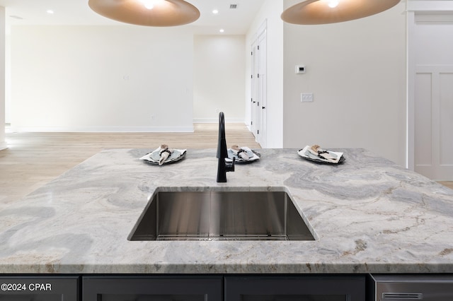 kitchen with light stone countertops, recessed lighting, a sink, and wood finished floors